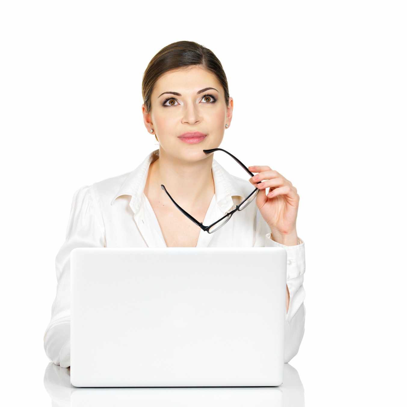 A professional woman holding eyeglasses sits in front of a laptop, looking thoughtfully upward, as she engages the given project by the digital media agency serivces